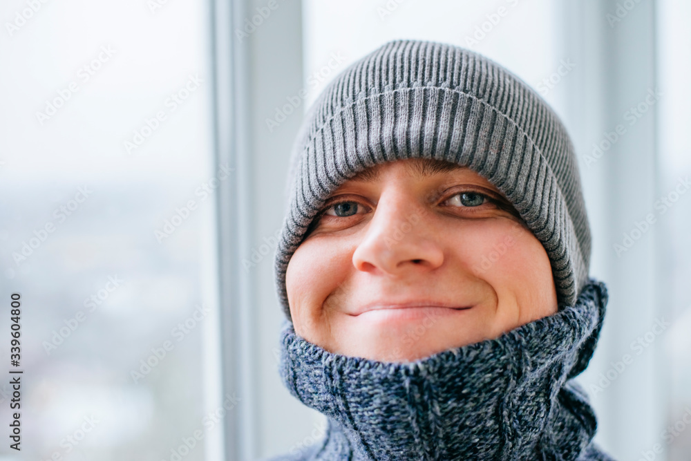 Young man feeling cold in flat near the window Young man feeling cold in flat near the window
