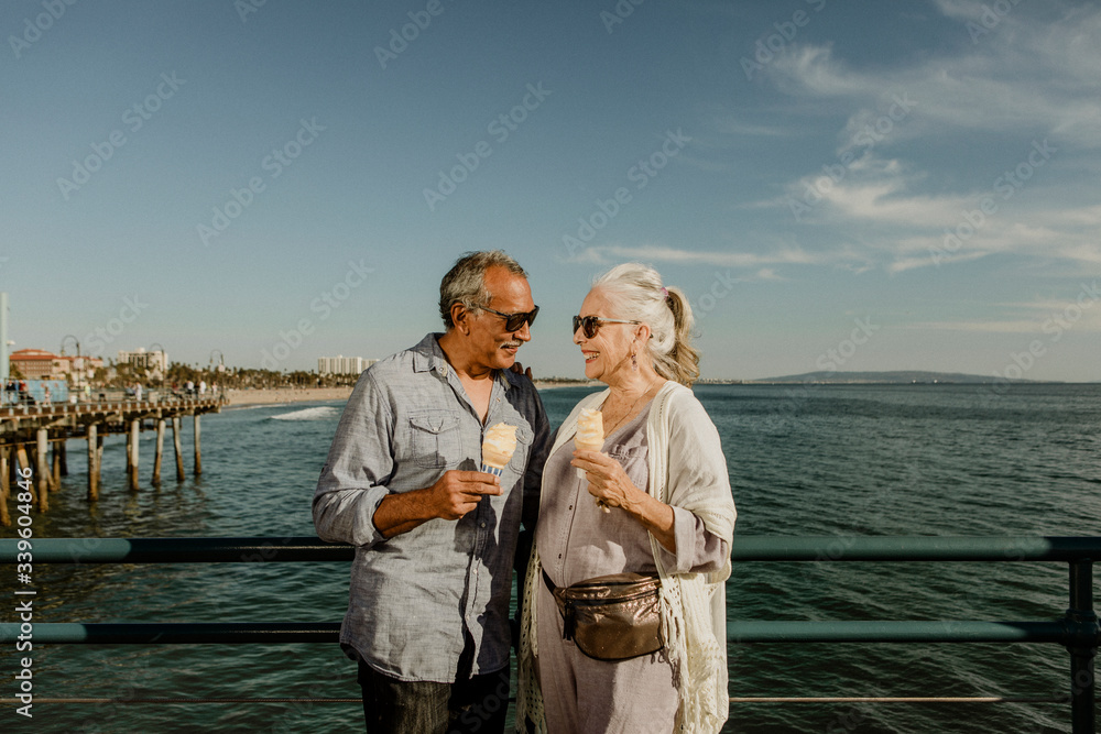 Happy couple enjoying ice cream by the sea