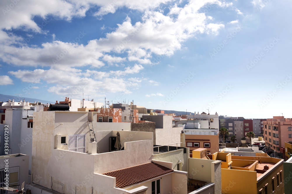Fototapeta premium Breathtaking sunrise seen from the roofs of traditional houses in El Medano with Mount Teide volcano in background, Tenerife, Canary Islands, Spain, sunny blue sky with copy space