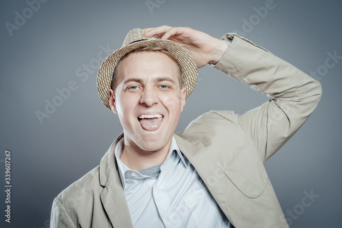Fotografie, Tablou Happy businessman in hat  standing against isolated gray background