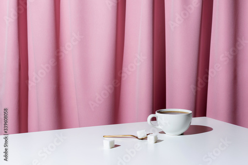 Cup of tea or coffee on white table in front of pink drapery, selective focus