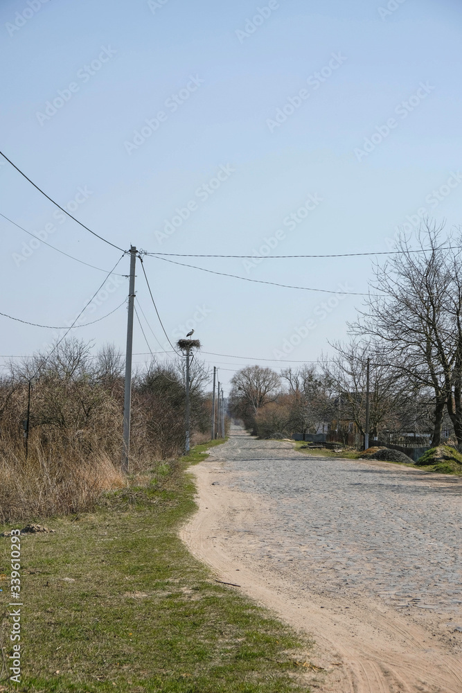 Deserted rural street in Ukraine. Masonry on the road on the old technology. Stork nest on an electric pole. Copy space.