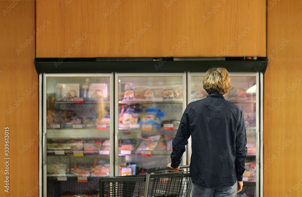 Obraz premium Man choosing frozen food from a supermarket freezer