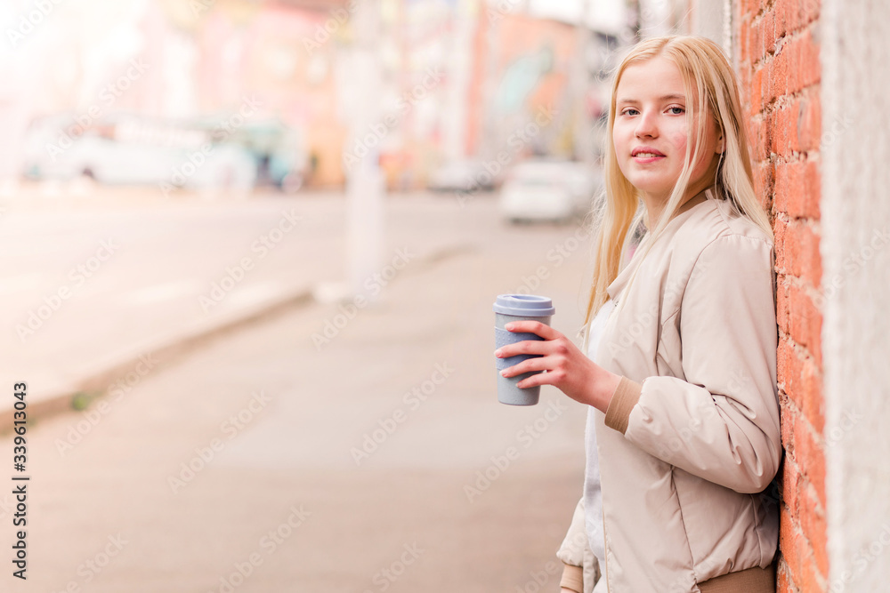 Portrait of young caucasian woman holding a cup of coffee against brick wall. Urban concept. Portrait of young caucasian woman holding a cup of coffee against brick wall. Urban concept.