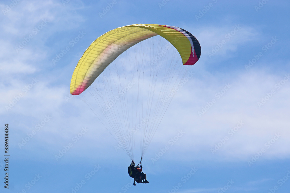 Tandem Paraglider flying wing in a blue sky Tandem Paraglider flying wing in a blue sky