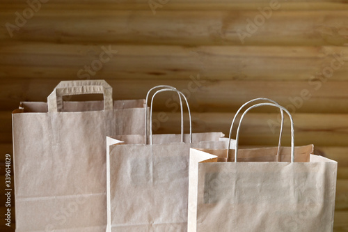 Three brown carton paper bags with handles on the wooden background with copy space