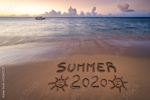 Handwritten Summer 2020 on sandy beach at sunset