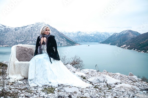 Beautyful bride sitting on a lake in winter mountances photo