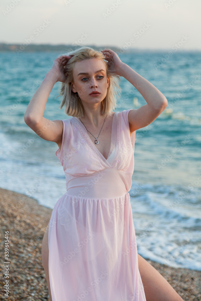 Portrait of a beautiful fashionable blonde woman on an empty beach by the sea Portrait of a beautiful fashionable blonde woman on an empty beach by the sea