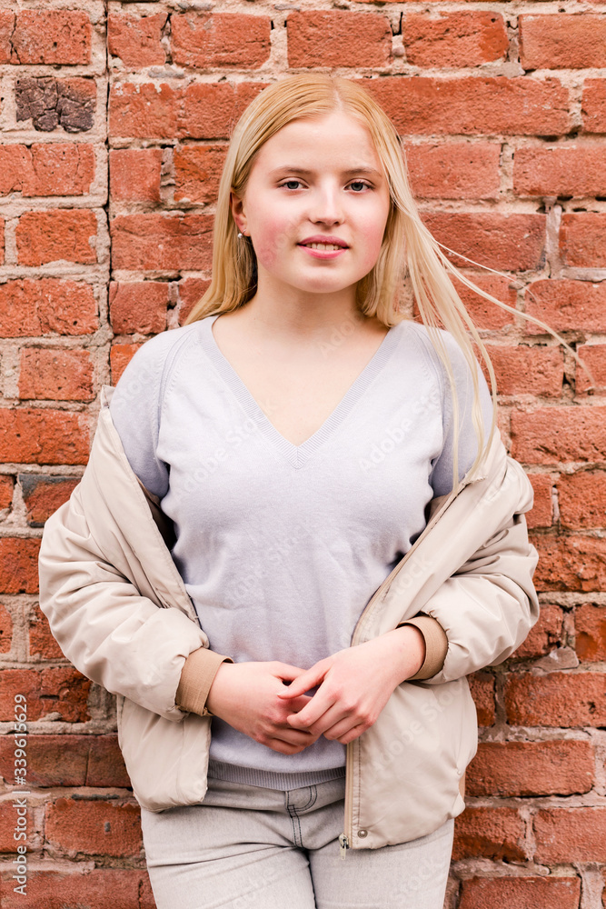 Beautiful blonde girl posing near a brick wall Beautiful blonde girl posing near a brick wall