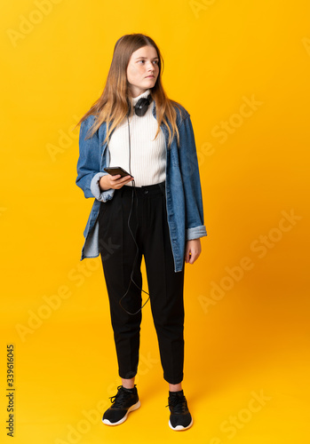 Student ukrainian teenager girl over isolated yellow background looking to the side © luismolinero