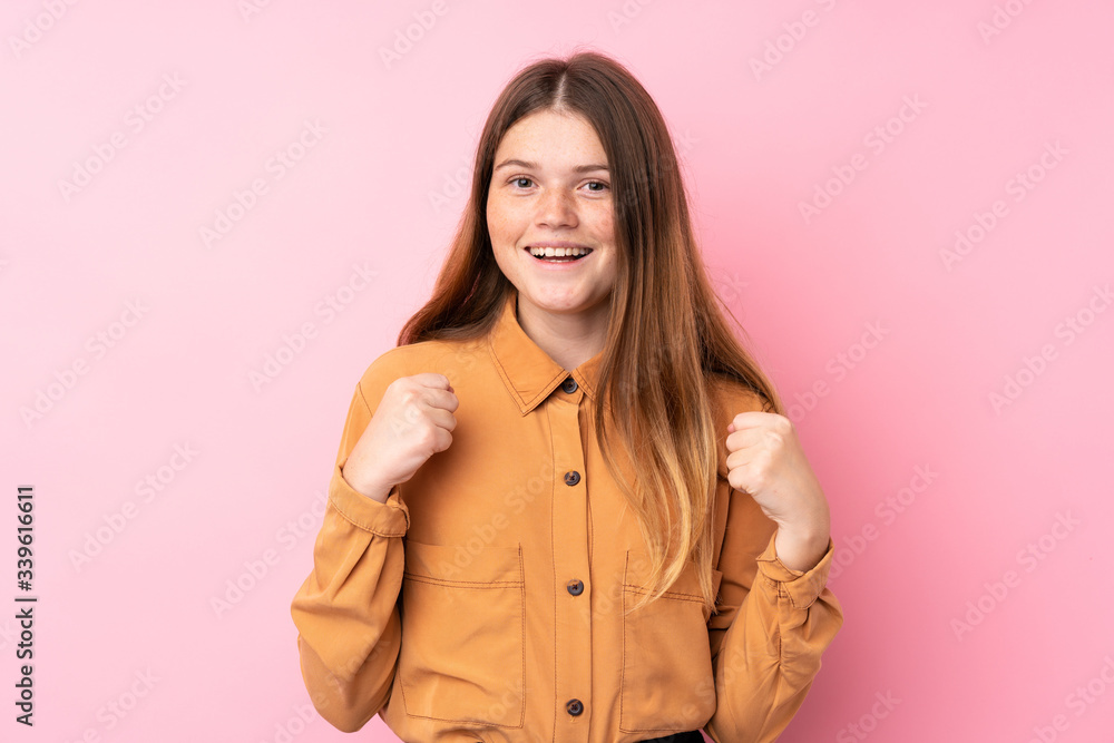 Ukrainian teenager girl over isolated pink background celebrating a victory in winner position Ukrainian teenager girl over isolated pink background celebrating a victory in winner position