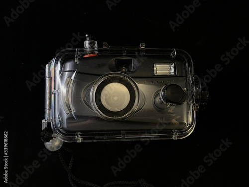 Film camera in a waterproof case, on a black background. Digital camera in a protective case. Equipment for underwater photography.