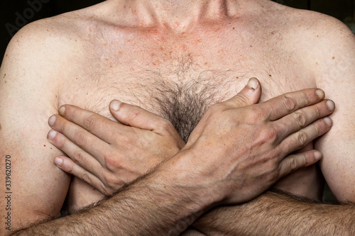 Caucasian man with his hands on his chest, black background