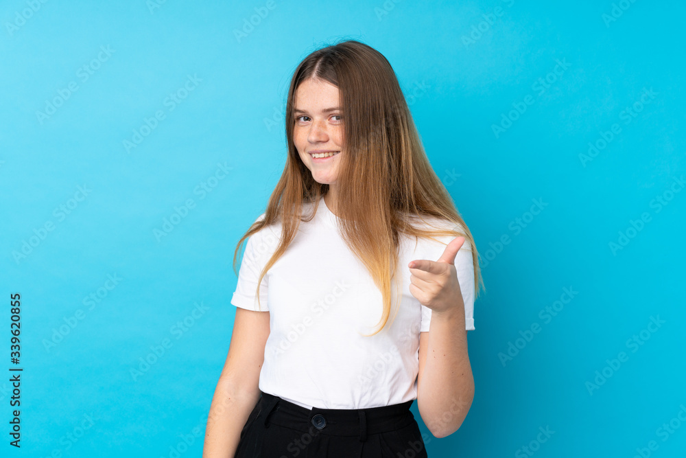 Ukrainian teenager girl over isolated blue background points finger at you Ukrainian teenager girl over isolated blue background points finger at you