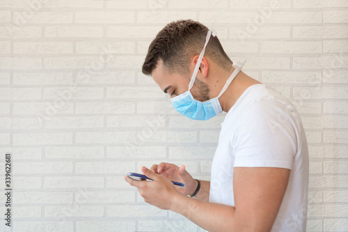 A man with a medical mask protecting against the virus or flu, in quarantine and communicating with his loved ones through his smartphone.