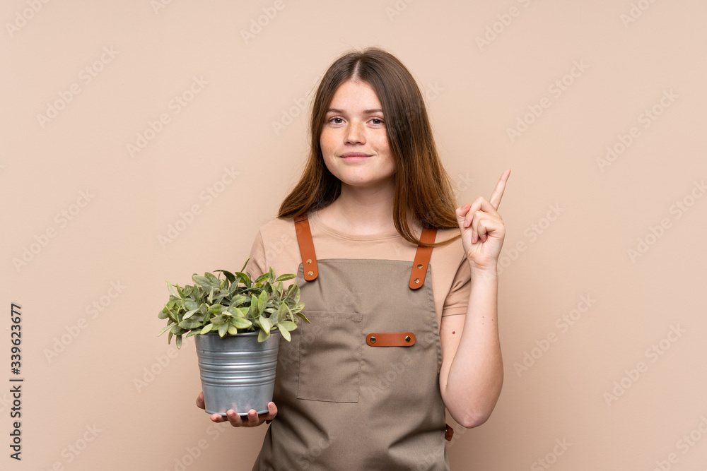 Ukrainian teenager gardener girl holding a plant pointing with the index finger a great idea Ukrainian teenager gardener girl holding a plant pointing with the index finger a great idea