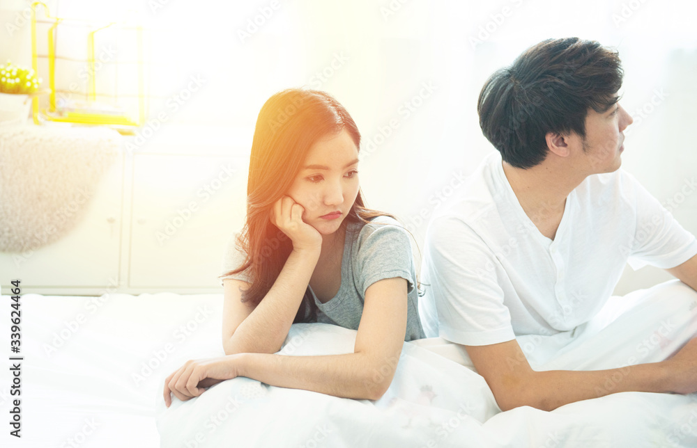 young asian couple in bed having problems and crisis man and woman hands cover head with confused unhappy separate from each other.Divorce and separation. young asian couple in bed having problems and crisis man and woman hands cover head with confused unhappy separate from each other.Divorce and separation.