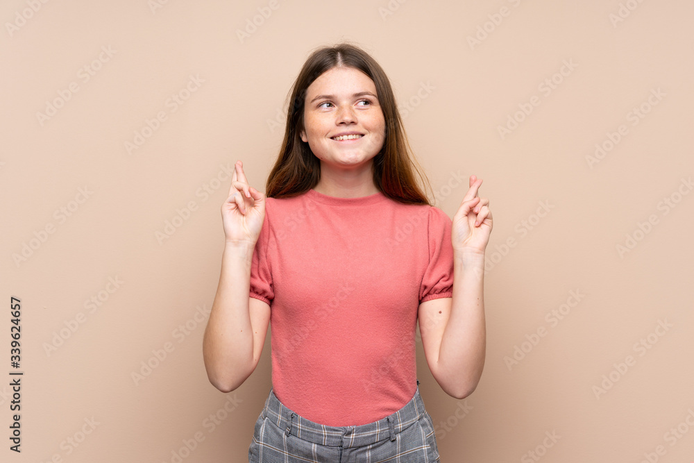 Ukrainian teenager girl over isolated background with fingers crossing Ukrainian teenager girl over isolated background with fingers crossing