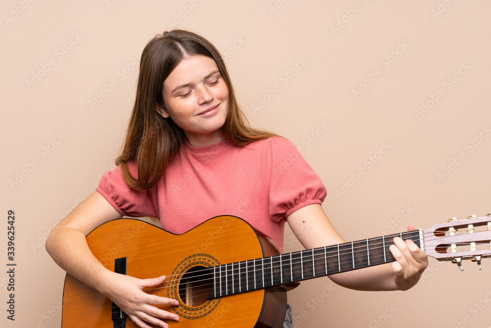 Ukrainian teenager girl with guitar over isolated background Ukrainian teenager girl with guitar over isolated background