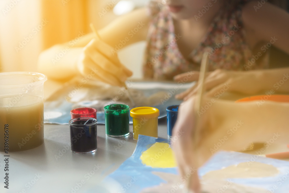 concept drawing. The child draws in gouache. On the table are jars of paint. Blurred hand of a child concept drawing. The child draws in gouache. On the table are jars of paint. Blurred hand of a child