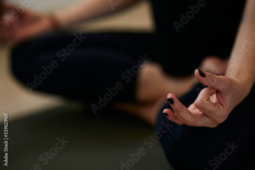Close up of slim Caucasian yogi woman sitting on the mat at home in lotus position and meditating.