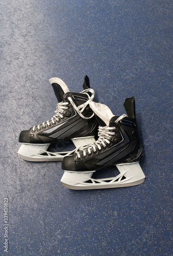 Hockey skates over floor in locker room with blue background and copy space. Vertical 