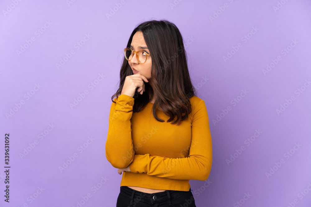 Young mixed race woman isolated on purple background having doubts and with confuse face expression Young mixed race woman isolated on purple background having doubts and with confuse face expression