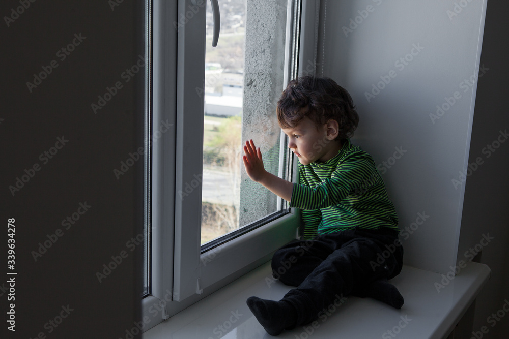 the child misses walks on the street and fresh air sitting on the windowsill by the window. the child misses walks on the street and fresh air sitting on the windowsill by the window.
