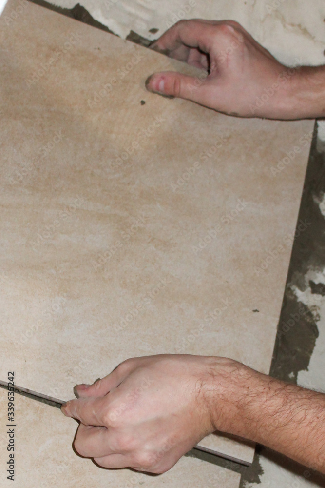 Installing ceramic tiles on the floor in the bath and toilet. The concept of reconstruction and improvement, home renovation, do-it-yourself workflow, accessories Installing ceramic tiles on the floor in the bath and toilet. The concept of reconstruction and improvement, home renovation, do-it-yourself workflow, accessories