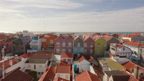 Flight over an traditional portuguese fisherman village in Costa Nova do Prado, Portugal. Street with colorful and striped houses. A drone flies over the village to the Atlantic Ocean.