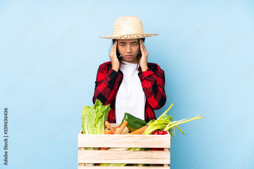 Young farmer Woman holding fresh vegetables in a wooden basket with headache