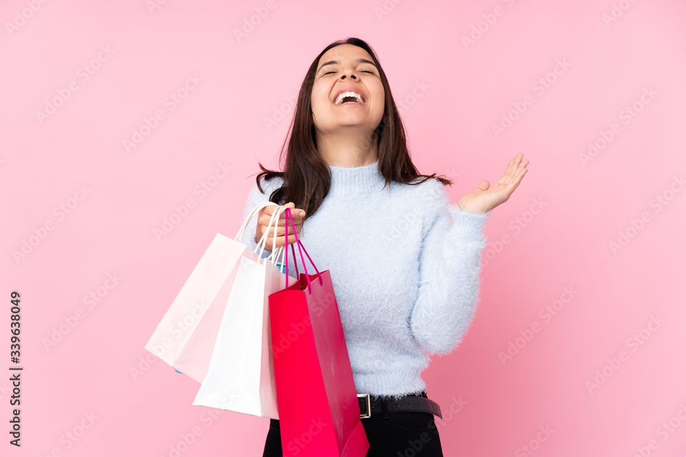 Young woman with shopping bag over isolated pink background smiling a lot Young woman with shopping bag over isolated pink background smiling a lot
