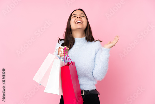 Young woman with shopping bag over isolated pink background smiling a lot