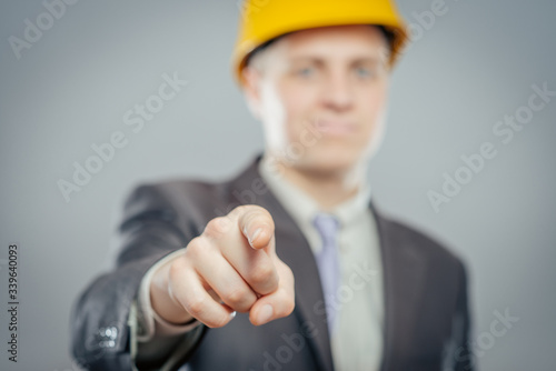 Fotografija young  man in a yellow helmet pointing at someone gesture with finger