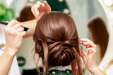 Young woman is receiving makeup and hairstyle by professional makeup artist and hairdresser in beauty salon.