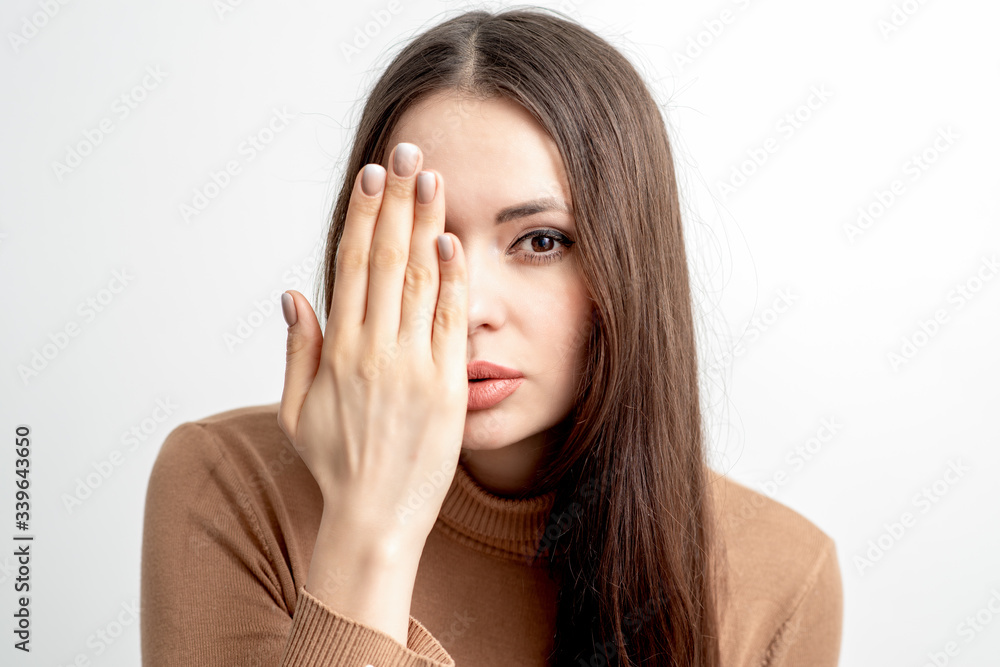 Portrait of beautiful woman covers her face by hand with beige manicure on white background. Portrait of beautiful woman covers her face by hand with beige manicure on white background.