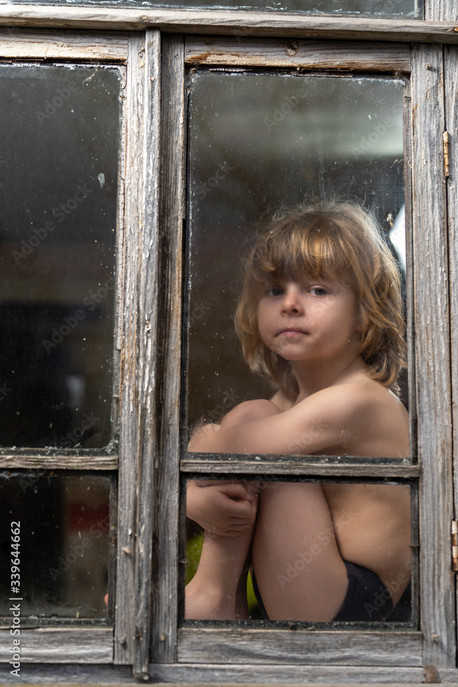 a boy with blond hair sits on a windowsill a boy with blond hair sits on a windowsill