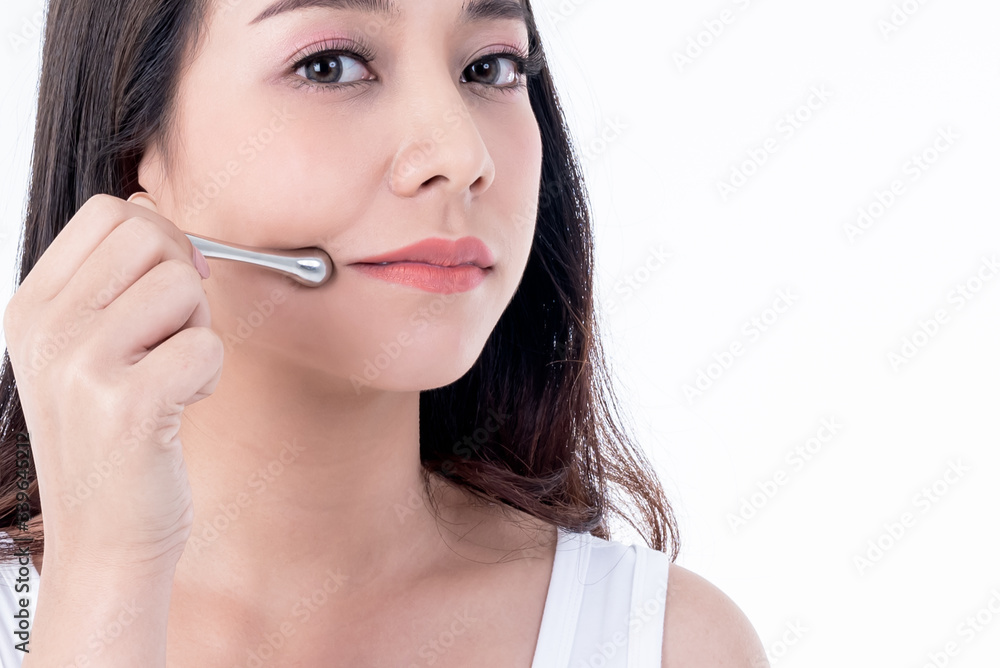 Portrait images of Asian young, pretty woman is 25 years old, She is using stainless steel bars Massage the skin around the lips to help reduce wrinkles and tighten the skin, to beauty concept. Portrait images of Asian young, pretty woman is 25 years old, She is using stainless steel bars Massage the skin around the lips to help reduce wrinkles and tighten the skin, to beauty concept.