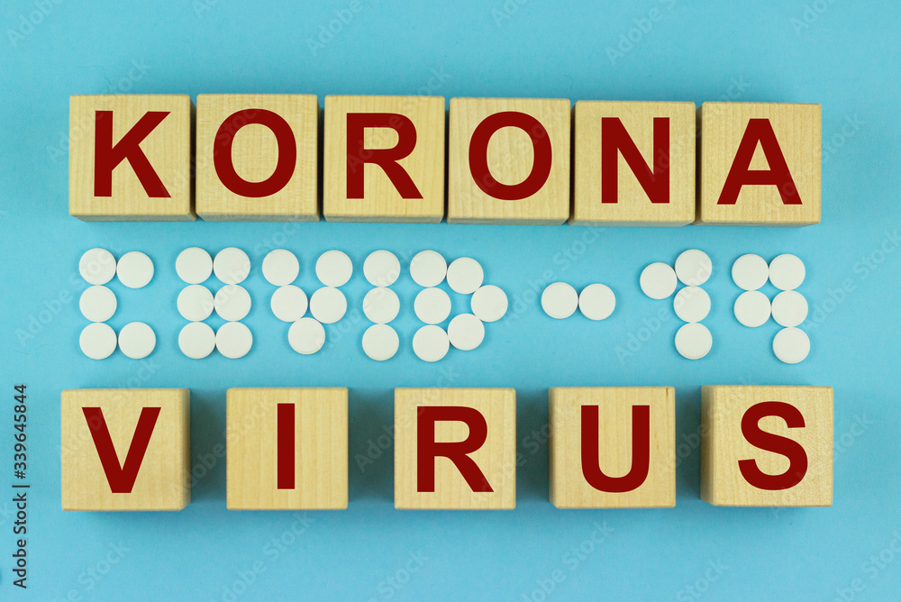 The korona virus is written on wooden cubes and the inscription covid19 of white tablets on blue background The korona virus is written on wooden cubes and the inscription covid19 of white tablets on blue background