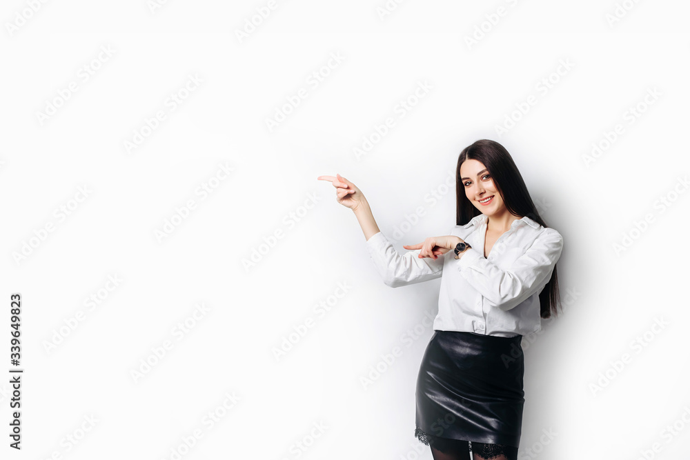 Young beautiful brunette businesswoman smiling looking at camera pointing finger in side over white background. Young beautiful brunette businesswoman smiling looking at camera pointing finger in side over white background.
