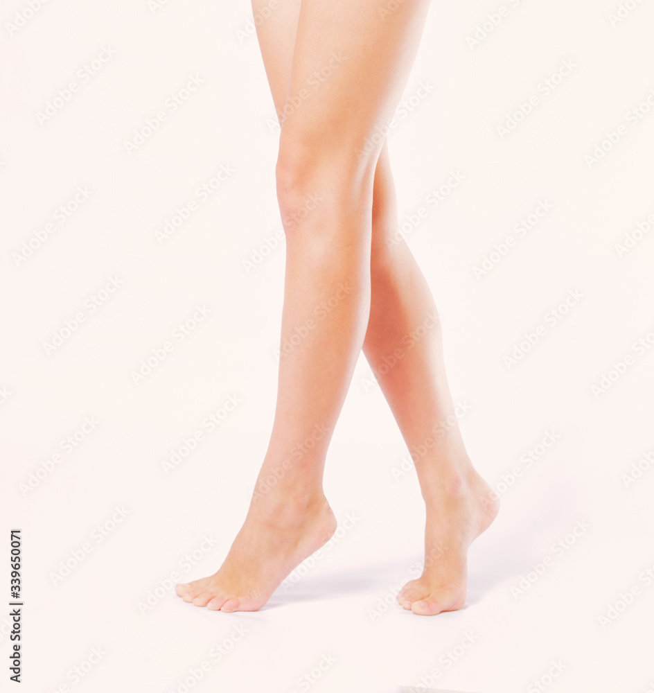 A young woman's bare feet stand barefoot on the floor with her legs crossed.