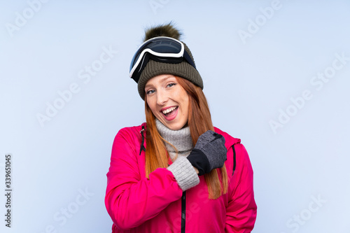 Skier redhead woman with snowboarding glasses over isolated blue wall celebrating a victory © luismolinero