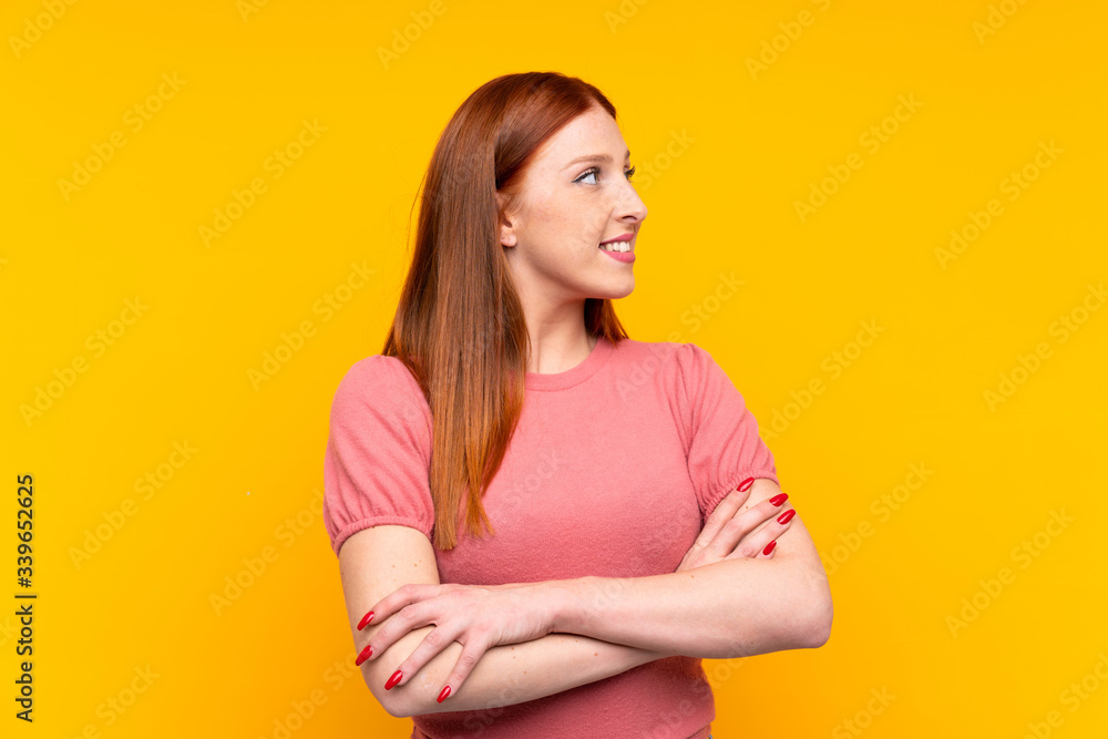 © luismolinero - Young redhead woman over isolated yellow background looking to the side