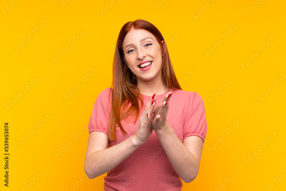 Young redhead woman over isolated yellow background applauding Young redhead woman over isolated yellow background applauding