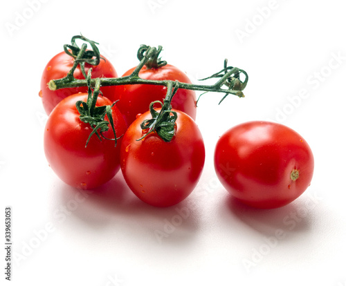 Group of red tomatoes on a white background. Four tomatoes on a branch and one next. Close-up.