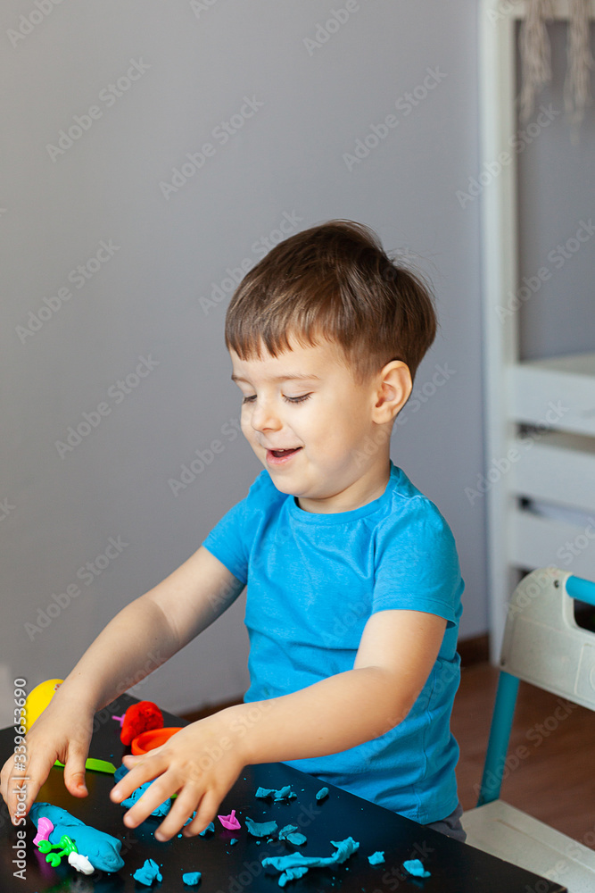 Boy playing with colorful clay molding in your room a Small child sculpts at home. Educational games for preschool children Boy playing with colorful clay molding in your room a Small child sculpts at home. Educational games for preschool children