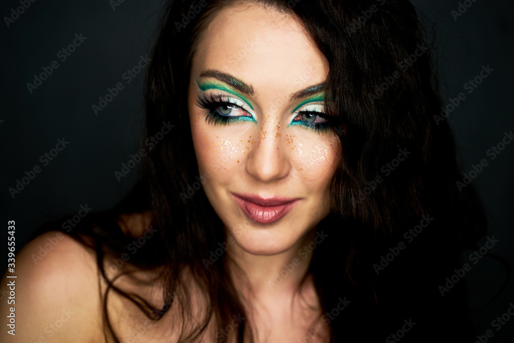 Fototapeta premium Beautiful young girl in the studio . The face of a young beautiful girl with a bright green make-up. Fashion, beauty, make-up, cosmetics, hairstyle, beauty salon, boutique, discounts, sales.