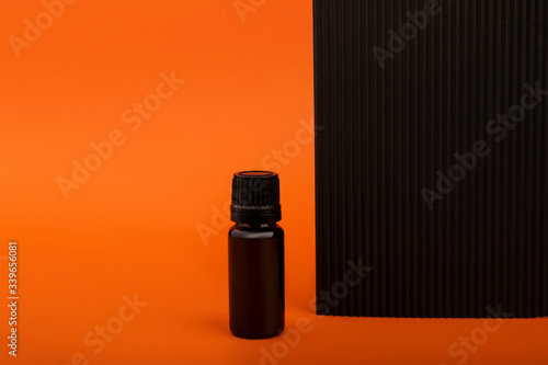 Essential Aromatherapy Oils. Glass dark bottles on an orange and black background.Photo mockup for your product