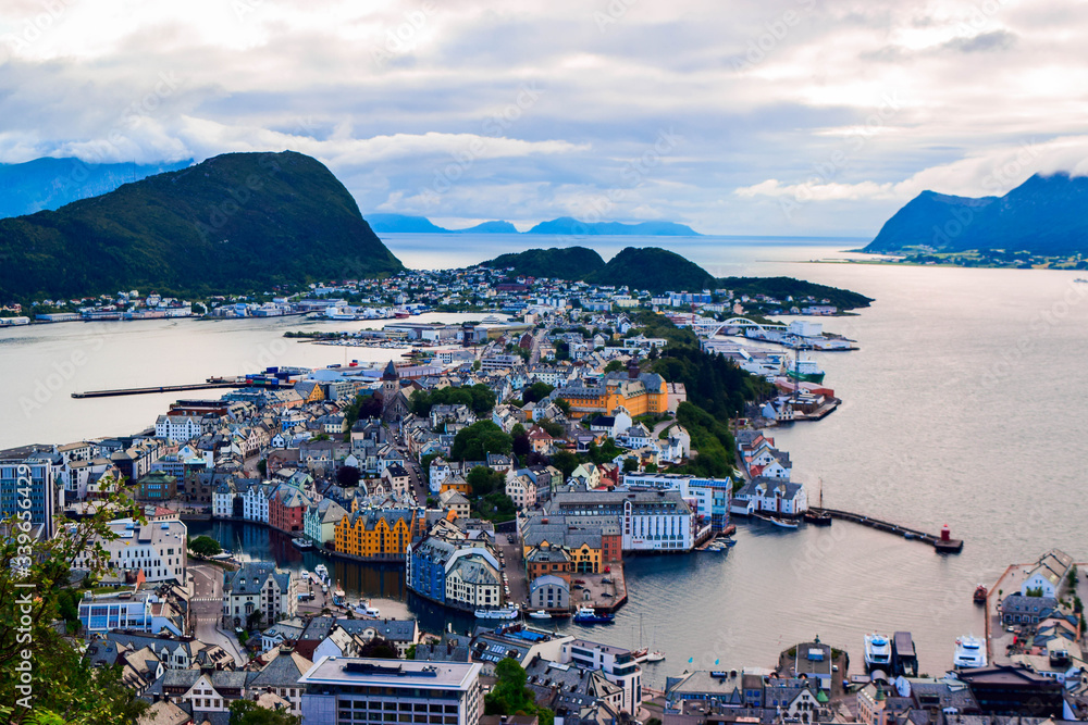 The amazing sunset over Alesund cityscape. Neoclassical and neo-Gothic stone buildings. Art Nouveau architecture. Sun rays illuminate Atlantic Ocean and islands. View from Aksla viewpoint. Norway.